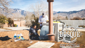 two bosque employees on a roof installing a new air conditioning unit
