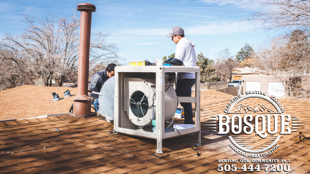 two bosque HCP employees doing air conditioning service on a roof